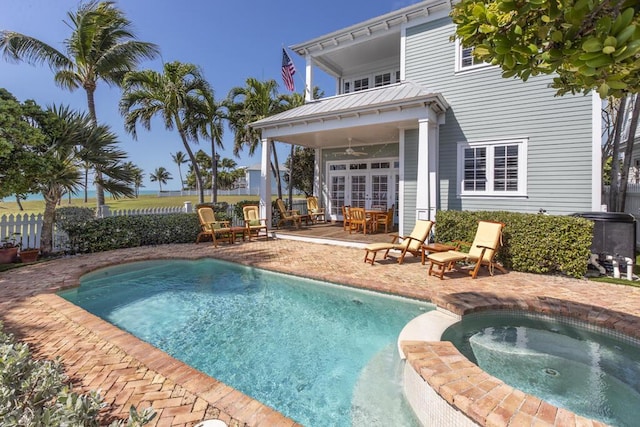 view of swimming pool featuring a patio area, a pool with connected hot tub, fence, and a ceiling fan