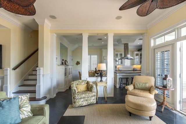 interior space with wainscoting, ceiling fan, ornamental molding, stairs, and ornate columns