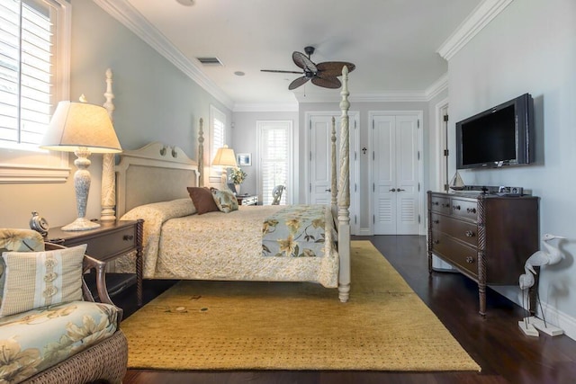 bedroom featuring dark wood-style floors, crown molding, visible vents, a ceiling fan, and baseboards