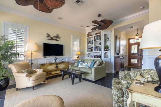 living area featuring visible vents, dark tile patterned flooring, wainscoting, ceiling fan, and crown molding