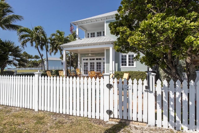 view of front of property with a fenced front yard, metal roof, covered porch, a standing seam roof, and a gate