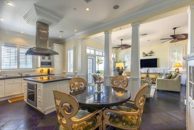 dining area with ornamental molding, a wealth of natural light, a wainscoted wall, and decorative columns