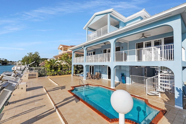 rear view of property featuring a patio area, a balcony, ceiling fan, and a water view