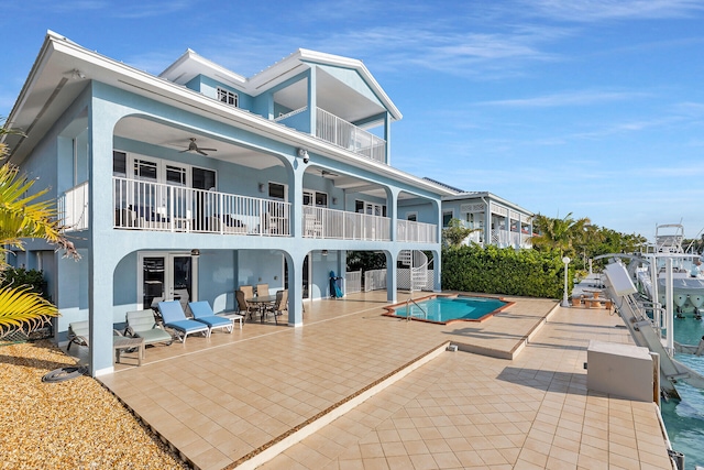 back of property with a balcony, ceiling fan, and a patio area