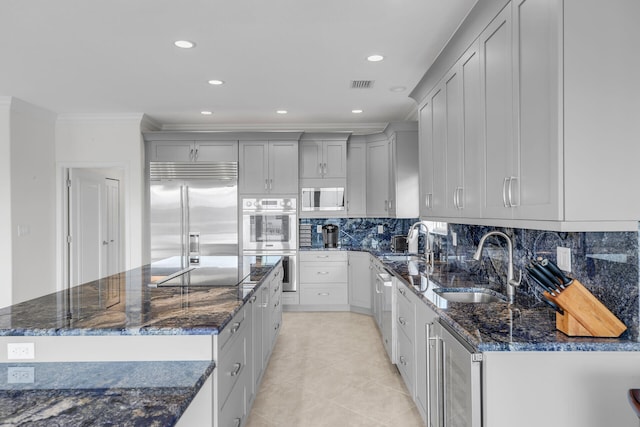 kitchen with built in appliances, sink, wine cooler, and dark stone counters