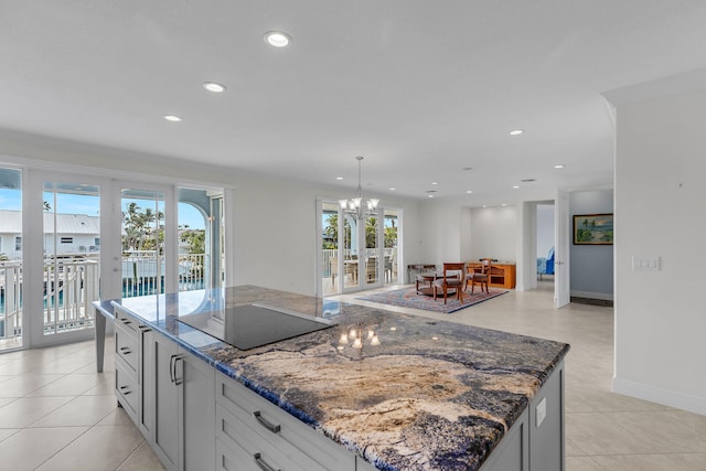 kitchen featuring decorative light fixtures, white cabinetry, dark stone countertops, a center island, and black electric cooktop