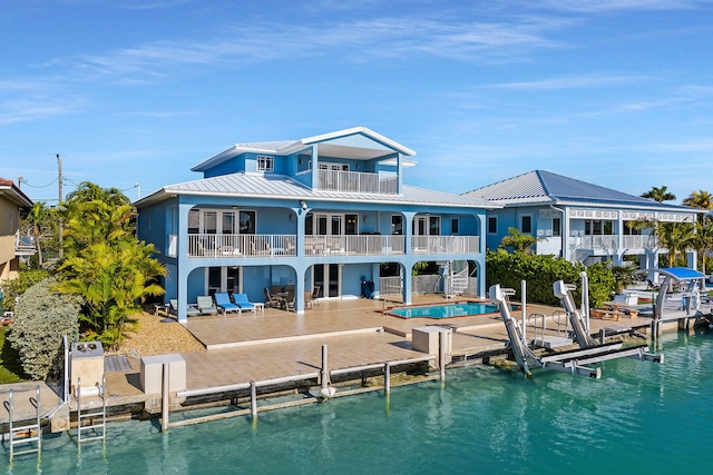 back of house with a water view, a balcony, and a patio