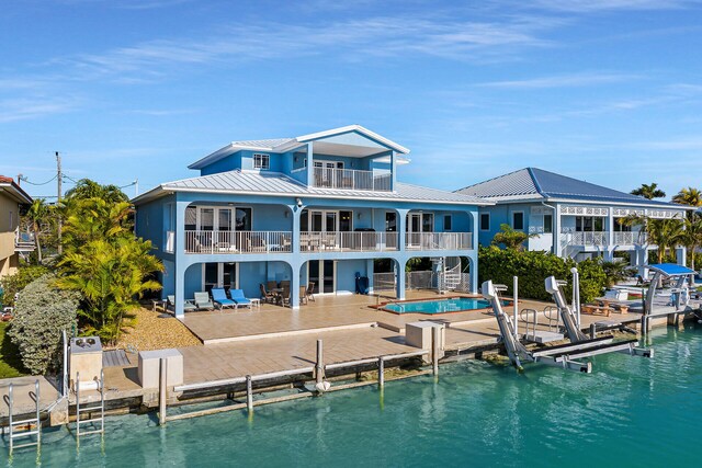 back of house with a water view, a balcony, and a patio