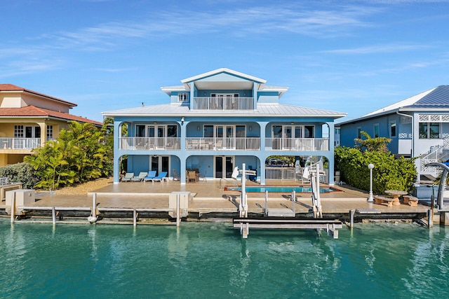 back of property featuring a patio area, a balcony, and a water view