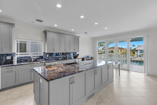 kitchen featuring dark stone countertops, sink, gray cabinets, and ornamental molding