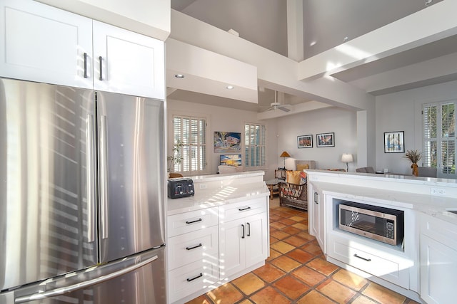 kitchen featuring light stone countertops, a wealth of natural light, stainless steel appliances, and white cabinets