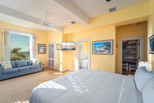 bedroom with a walk in closet, beam ceiling, and a closet