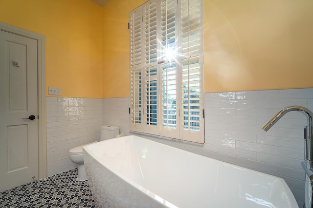 bathroom featuring tile patterned flooring, tile walls, a bathtub, and toilet