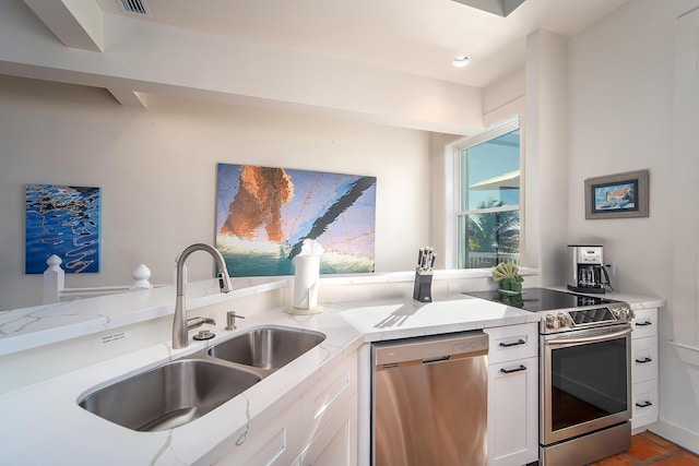 kitchen with white cabinetry, appliances with stainless steel finishes, sink, and light stone counters