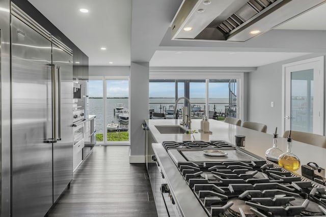 kitchen with a water view, stainless steel built in fridge, sink, and dark wood-type flooring