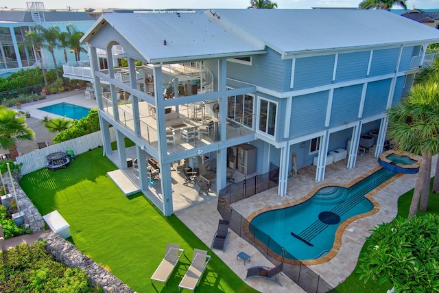 back of property featuring a patio, a balcony, an outdoor living space, a yard, and a fenced in pool