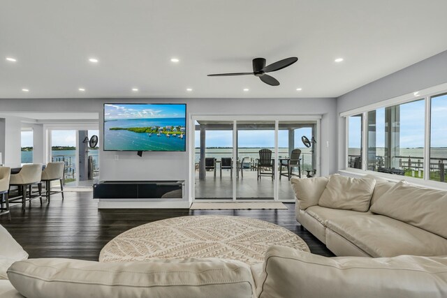 living room featuring dark wood-type flooring, ceiling fan, and a wealth of natural light