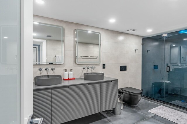 bathroom featuring a shower with door, tile walls, vanity, decorative backsplash, and toilet