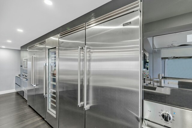 kitchen featuring wall oven, dark hardwood / wood-style flooring, and built in fridge