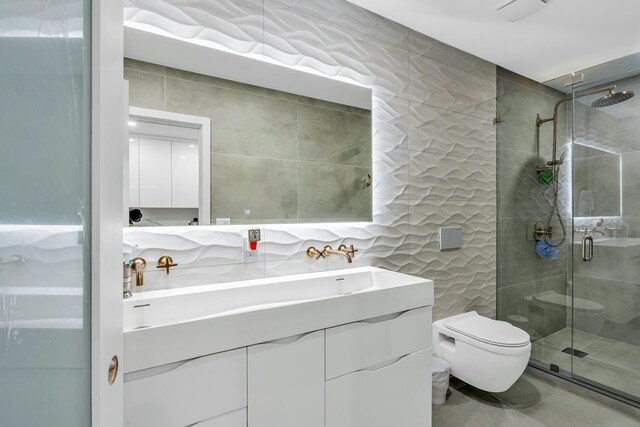 bathroom featuring tile walls, vanity, a shower with door, and toilet