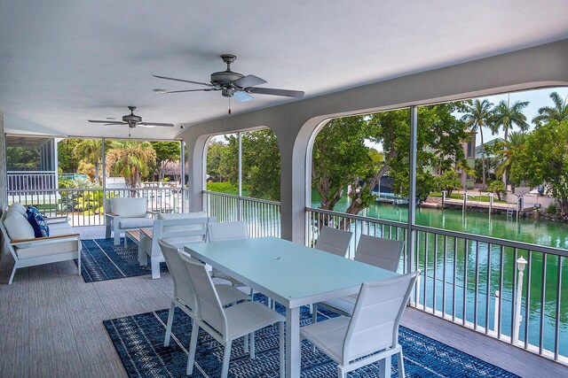 sunroom / solarium featuring a water view, ceiling fan, and a wealth of natural light