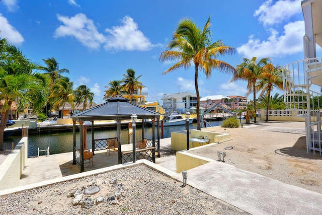view of dock featuring a gazebo, a water view, and a patio area