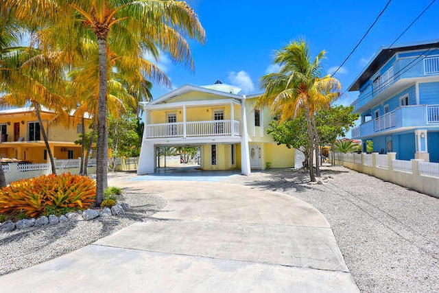 beach home with curved driveway, fence, and a carport