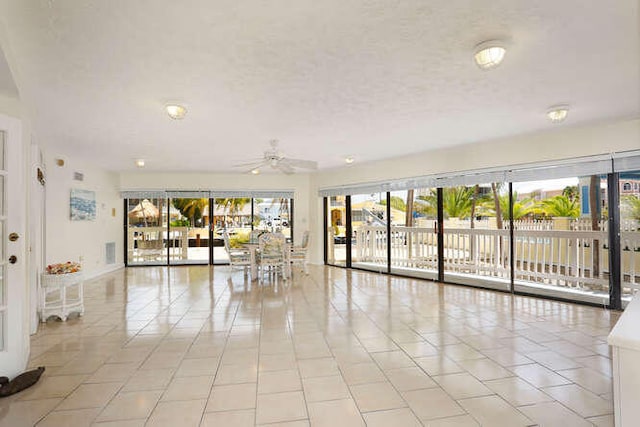 empty room with a healthy amount of sunlight, light tile patterned floors, and a ceiling fan