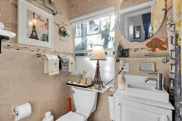 half bathroom with tile walls, toilet, and vanity