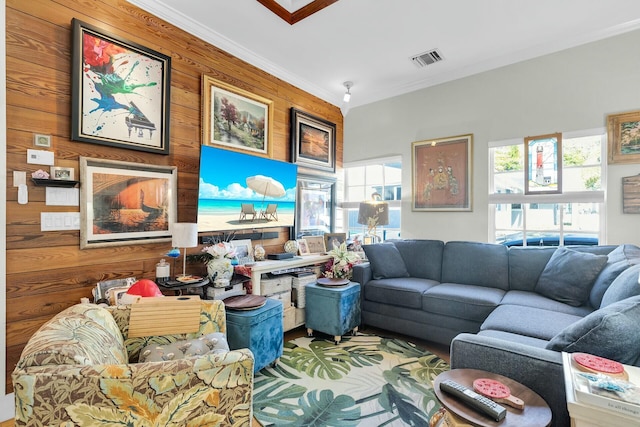 living room featuring wooden walls, visible vents, and ornamental molding