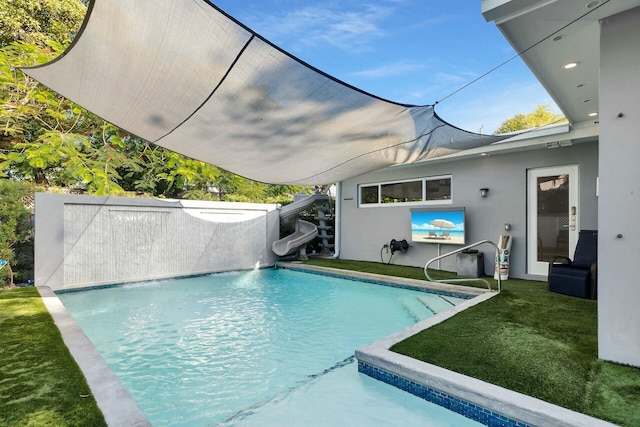 outdoor pool with a water slide and a lawn