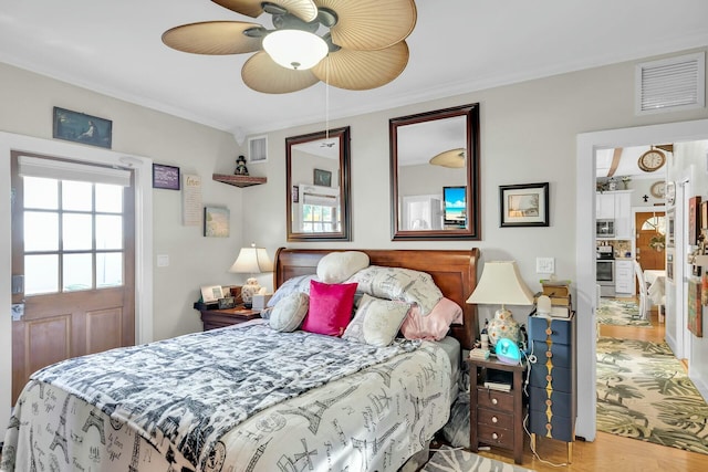 bedroom featuring ceiling fan, ornamental molding, wood finished floors, and visible vents