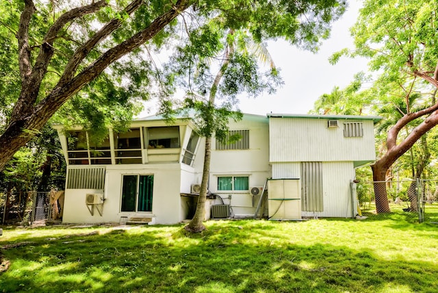 rear view of house with a sunroom, a yard, and central AC