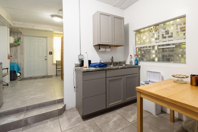 kitchen with light tile patterned flooring, gray cabinets, and sink