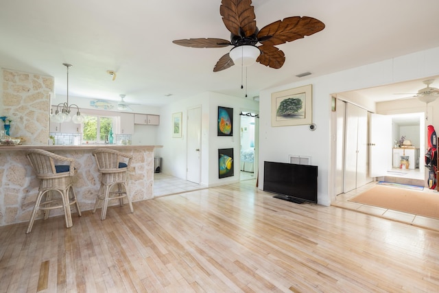 interior space with ceiling fan, decorative light fixtures, kitchen peninsula, and light hardwood / wood-style flooring