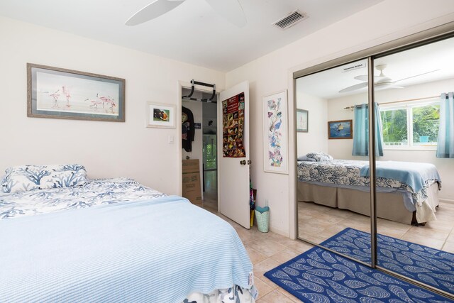 bedroom with light tile patterned flooring, ceiling fan, and a closet