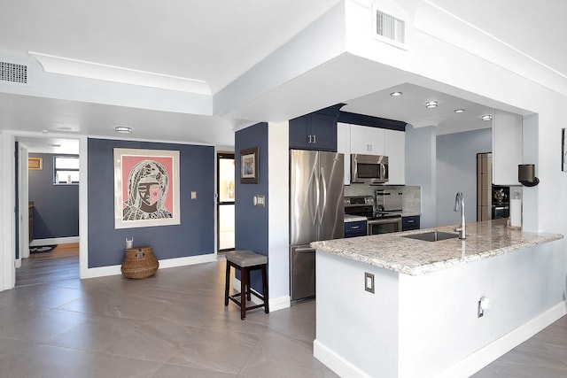 kitchen featuring appliances with stainless steel finishes, a breakfast bar, sink, kitchen peninsula, and light stone countertops