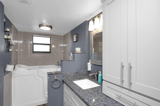 bathroom featuring washer / clothes dryer, vanity, and a bathtub