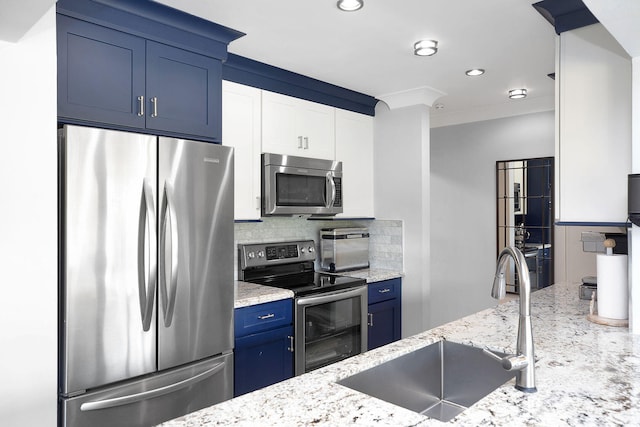 kitchen with blue cabinetry, sink, appliances with stainless steel finishes, light stone countertops, and decorative backsplash