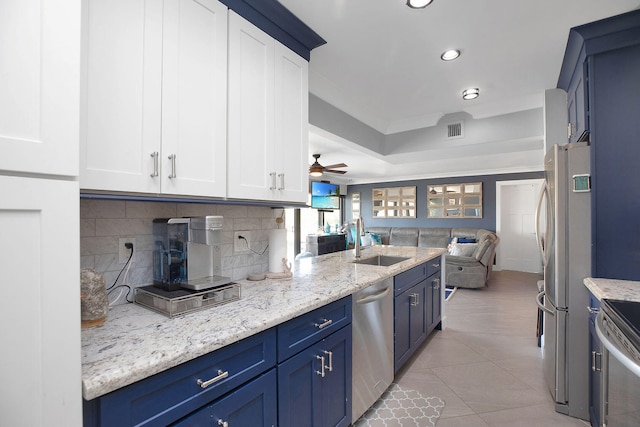 kitchen with sink, decorative backsplash, stainless steel appliances, and blue cabinets