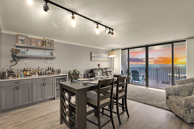 dining space with light hardwood / wood-style flooring, floor to ceiling windows, wine cooler, ornamental molding, and indoor bar