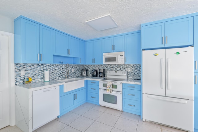 kitchen with light tile patterned floors, light countertops, decorative backsplash, a sink, and white appliances