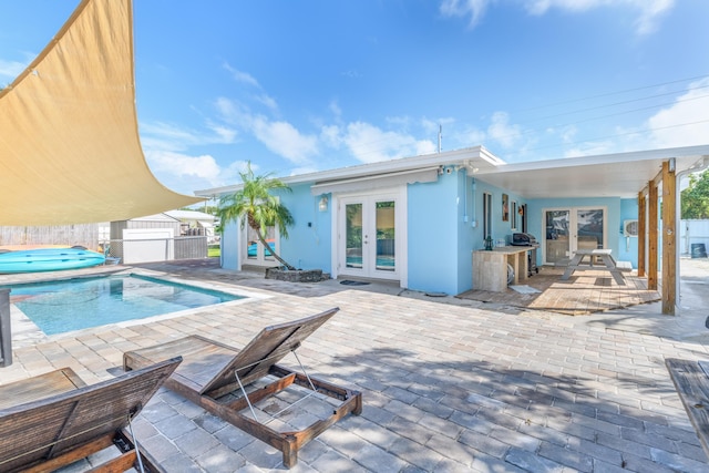 outdoor pool with area for grilling, french doors, a patio area, and fence