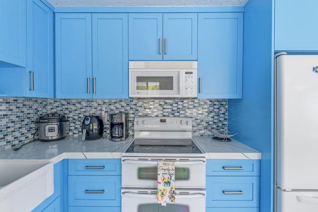 kitchen with light countertops, white appliances, blue cabinetry, and decorative backsplash