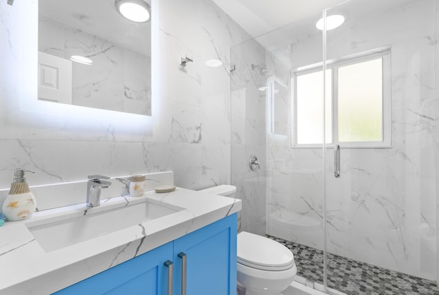 bathroom with vanity, a marble finish shower, toilet, and tile walls