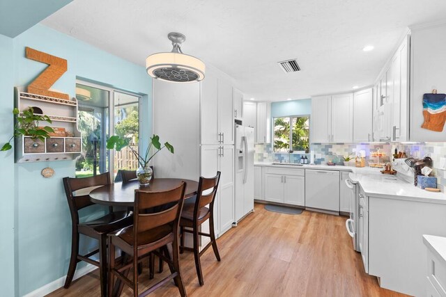 kitchen with sink, backsplash, white cabinets, light hardwood / wood-style floors, and white appliances