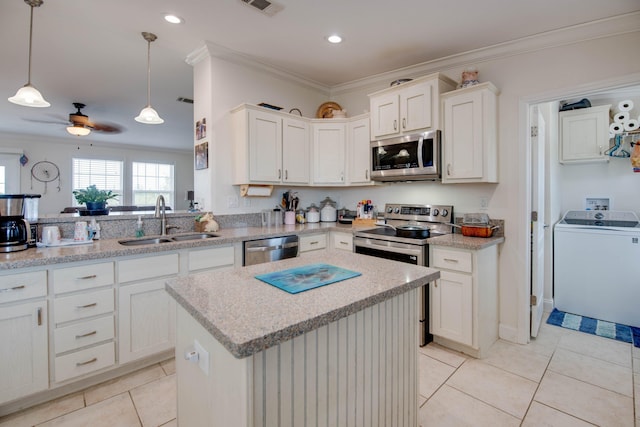 kitchen featuring sink, decorative light fixtures, a center island, stainless steel appliances, and washer / clothes dryer