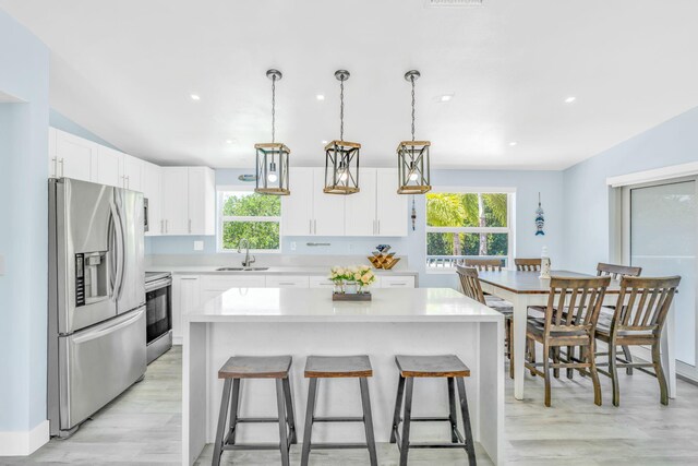 29012 Bigonia Dr, Big Pine, FL 33043 - kitchen with stainless steel appliances, a sink, light wood-style floors, light countertops, and a breakfast bar area