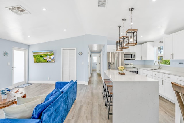 29012 Bigonia Dr, Big Pine, FL 33043 - kitchen with appliances with stainless steel finishes, open floor plan, light wood-style floors, a kitchen breakfast bar, and a sink