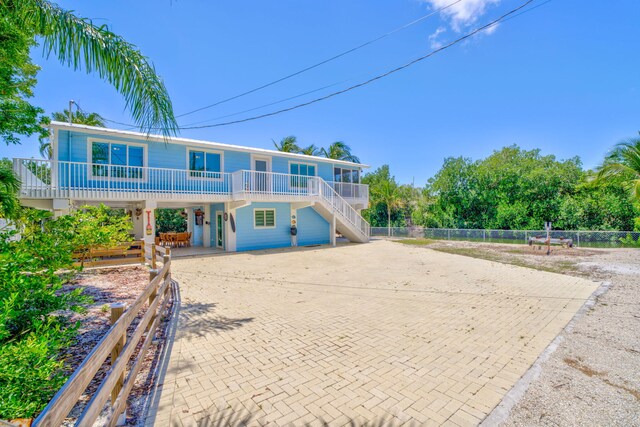 29012 Bigonia Dr, Big Pine, FL 33043 - back of house with decorative driveway, a carport, stairs, a porch, and fence